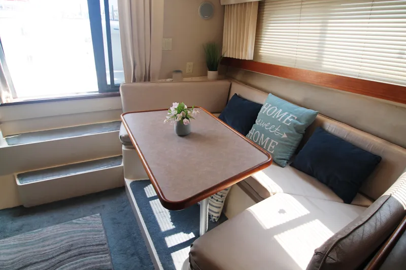 Slide: The Image of 1995 Carver 330 Mariner interior with cozy dining area, cushions, and natural light. - 30