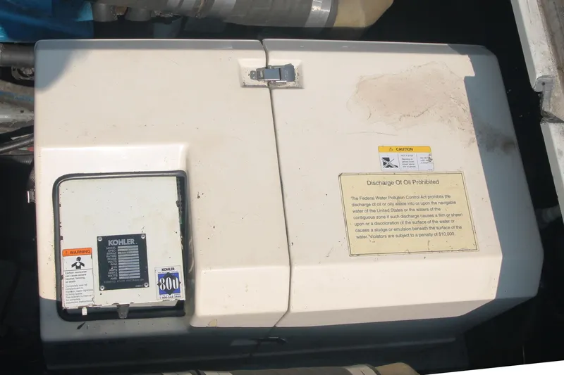Slide: The Image of 1995 Carver 330 Mariner engine compartment with Kohler generator and caution labels. - 50
