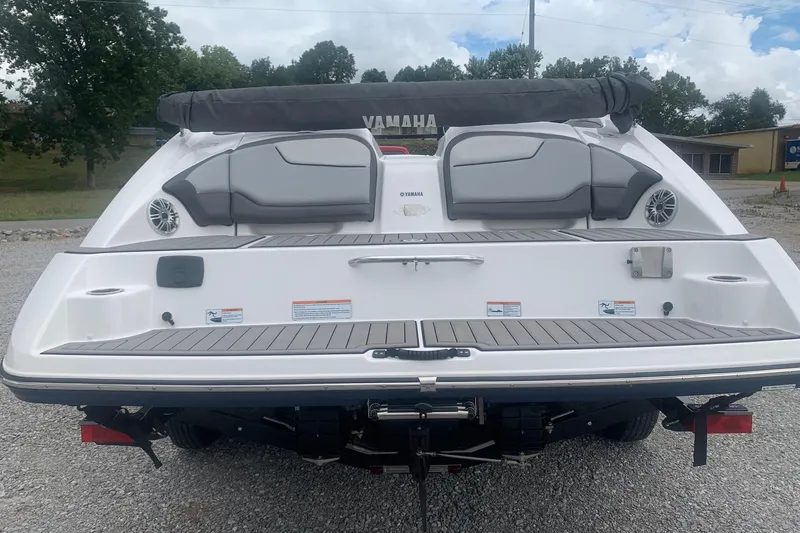 Slide: The Image of 2017 Yamaha Boats 212 Limited, rear view with seating and speakers, parked outdoors. - 2