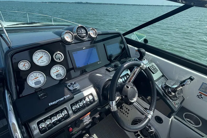 Slide: The Image of 2021 Formula 350ss boat dashboard with gauges, steering wheel, and navigation system on open water. - 21