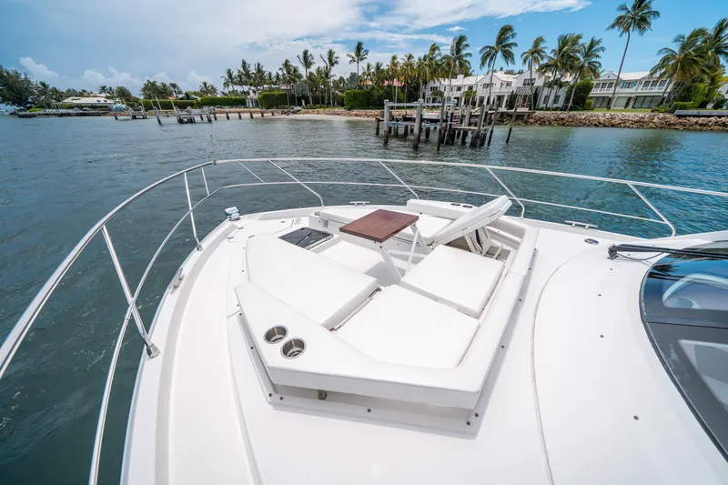 Slide: The Image of 2019 Cruisers Yachts Cantius with sun loungers, docked near palm-lined shore. - 14