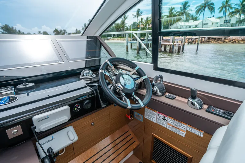 Slide: The Image of 2019 Cruisers Yachts Cantius helm with advanced navigation systems and scenic waterfront view. - 27