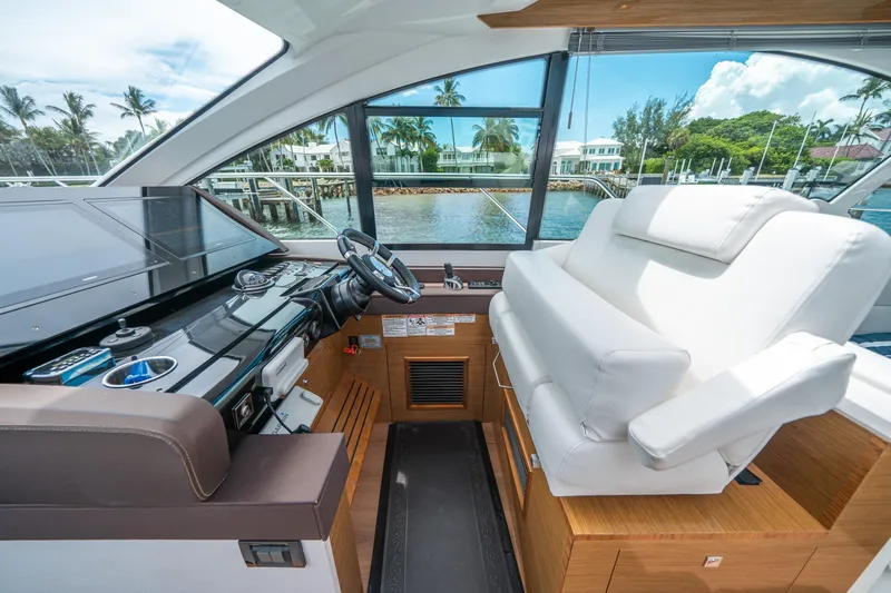 Slide: The Image of 2019 Cruisers Yachts Cantius helm with luxurious seating and modern controls, overlooking marina. - 30