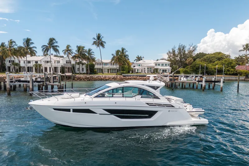Slide: The Image of 2019 Cruisers Yachts Cantius on water near luxury waterfront homes and palm trees. - 62