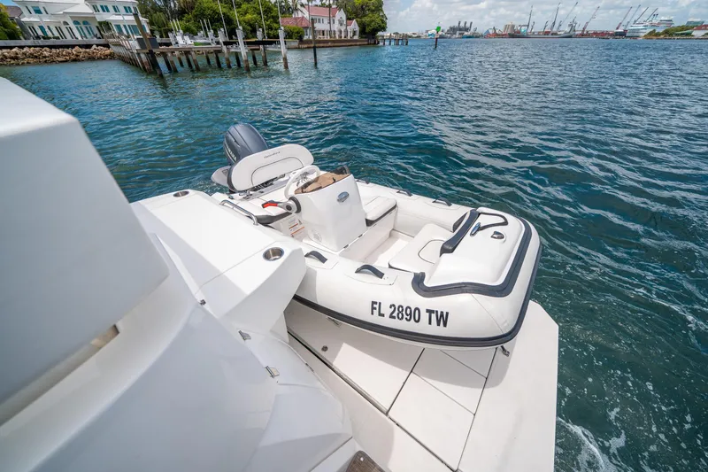 Slide: The Image of 2019 Cruisers Yachts Cantius with inflatable boat on water, dock and buildings in background. - 9