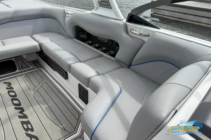 Slide: The Image of 2021 Moomba Craz boat interior with gray seating and blue accents, dockside view. - 10