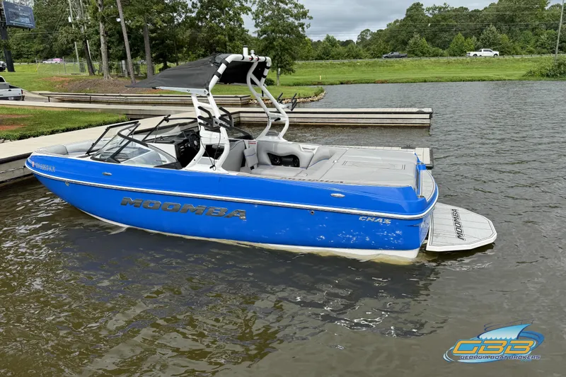 Slide: The Image of 2021 Moomba Craz boat in blue, docked on a calm lake. - 3