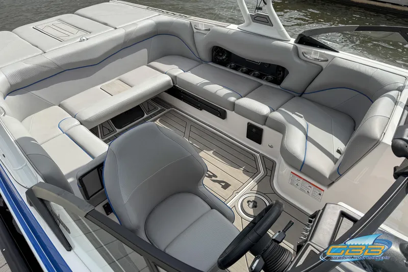 Slide: The Image of 2021 Moomba Craz boat interior with gray seating and steering wheel, docked by water. - 4
