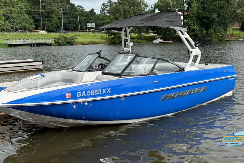 Slide: The Image of 2021 Moomba Craz boat in blue, docked on a calm lake. - 6