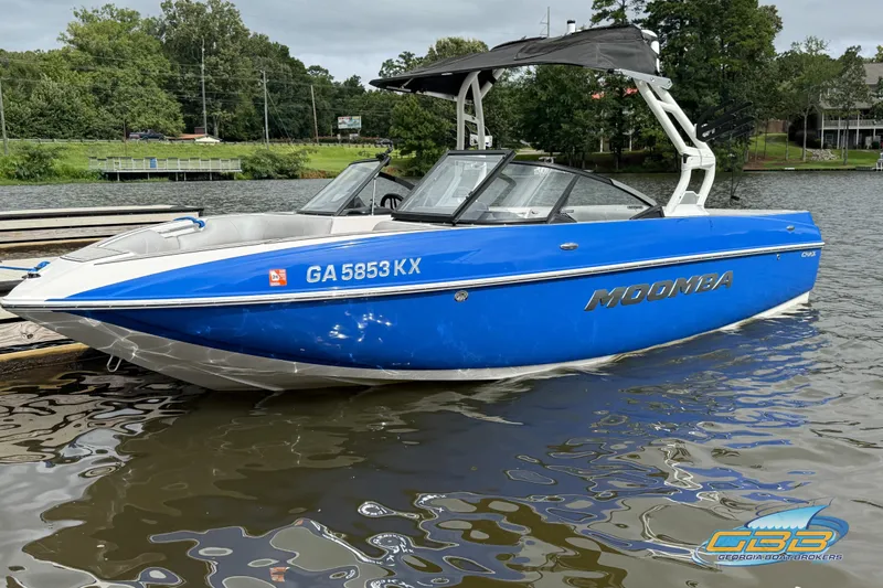 Slide: The Image of 2021 Moomba Craz boat in blue, docked on a calm lake. - 7
