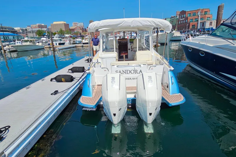 Slide: The Image of 2023 MJM 35 boat docked at marina with twin engines and cityscape background. - 12