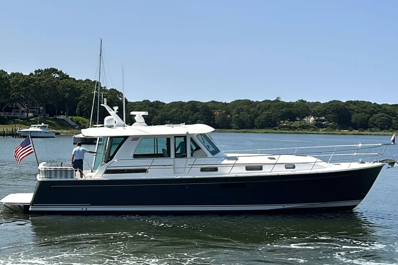 Slide: The Image of 2022 Sabre 48 Salon Express yacht cruising on a serene lake under a blue sky. - 4