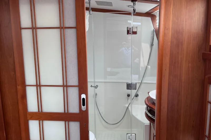 Slide: The Image of 2022 Sabre 48 Salon Express yacht cruising on a serene lake under a partly cloudy sky. - 45