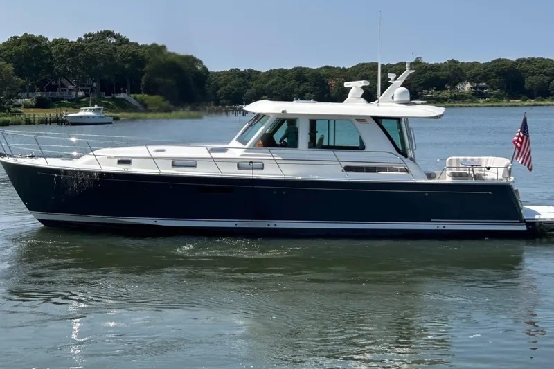 Slide: The Image of 2022 Sabre 48 Salon Express yacht on a serene river with lush forest backdrop. - 5