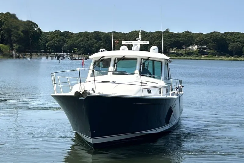 Slide: The Image of 2022 Sabre 48 Salon Express yacht deck with seating and table, overlooking serene water. - 6