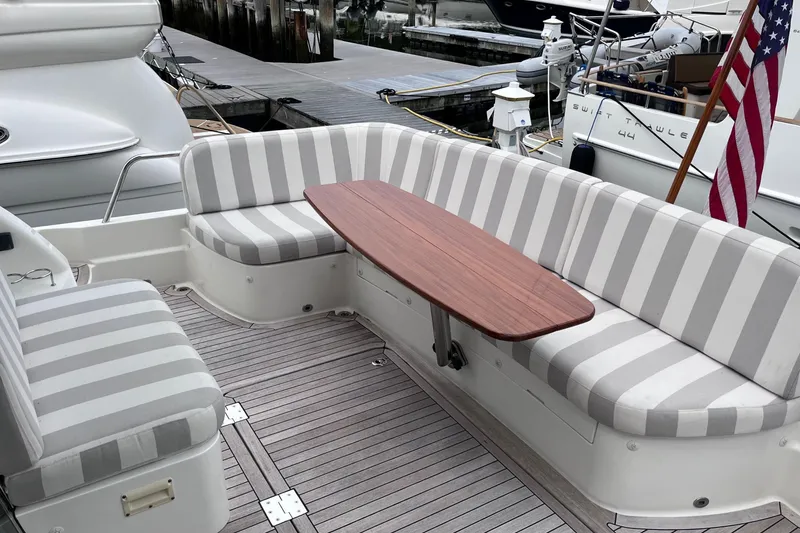 Slide: The Image of 2022 Sabre 48 Salon Express yacht with striped seating, docked by a scenic lake. - 8