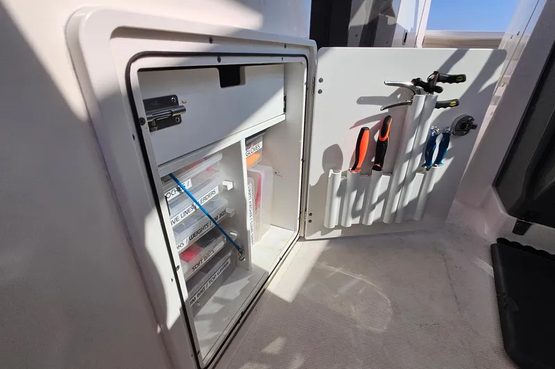 Slide: The Image of Storage compartment with tools and labeled boxes on a 2018 Pursuit DC 295 Dual Console boat. - 21