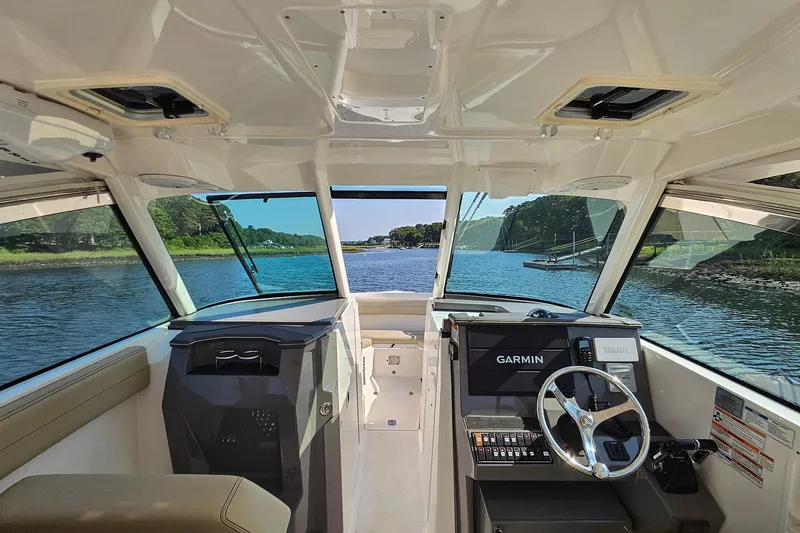 Slide: The Image of 2018 Pursuit DC 295 Dual Console boat interior with Garmin navigation, steering wheel, and scenic water view. - 25