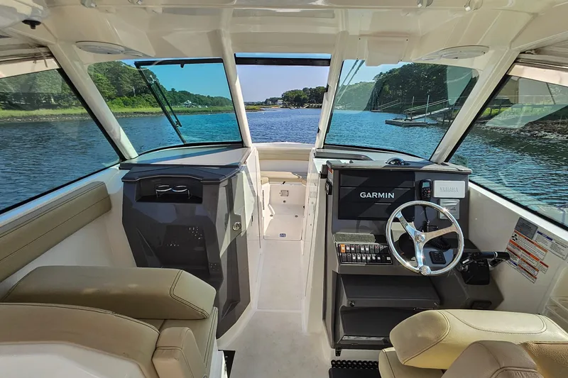Slide: The Image of 2018 Pursuit DC 295 Dual Console interior with Garmin navigation, steering wheel, and scenic water view. - 26