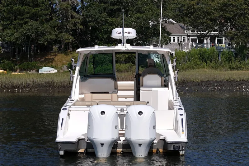Slide: The Image of 2018 Pursuit DC 295 Dual Console boat with twin engines on a calm waterway. - 6
