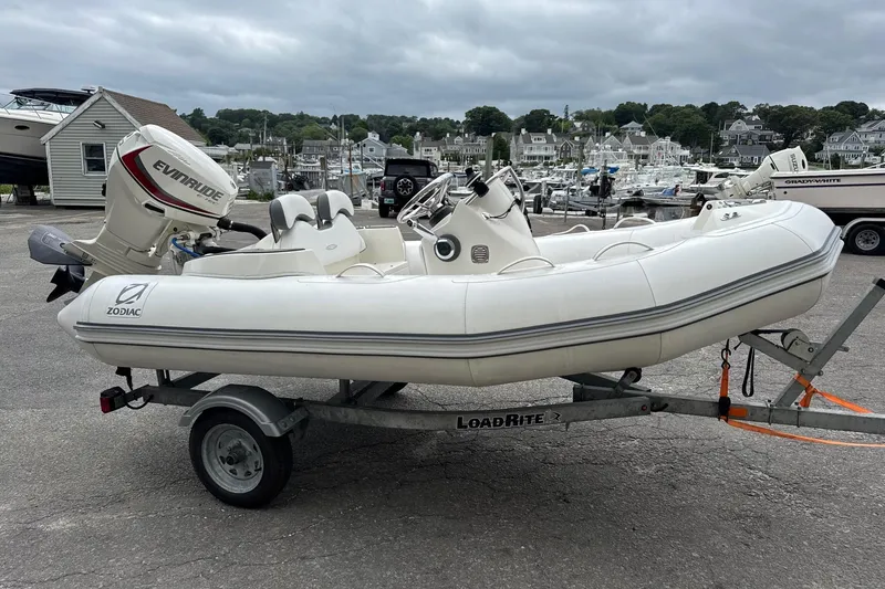 Slide: The Image of 2021 Zodiac Yachtline 360 inflatable boat on trailer, with Evinrude outboard motor, dockside. - 3