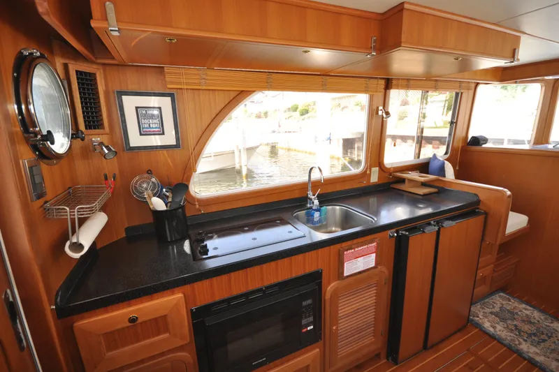 Slide: The Image of 2015 Helmsman Trawlers 31 Sedan kitchen with wood cabinetry and waterfront view. - 16