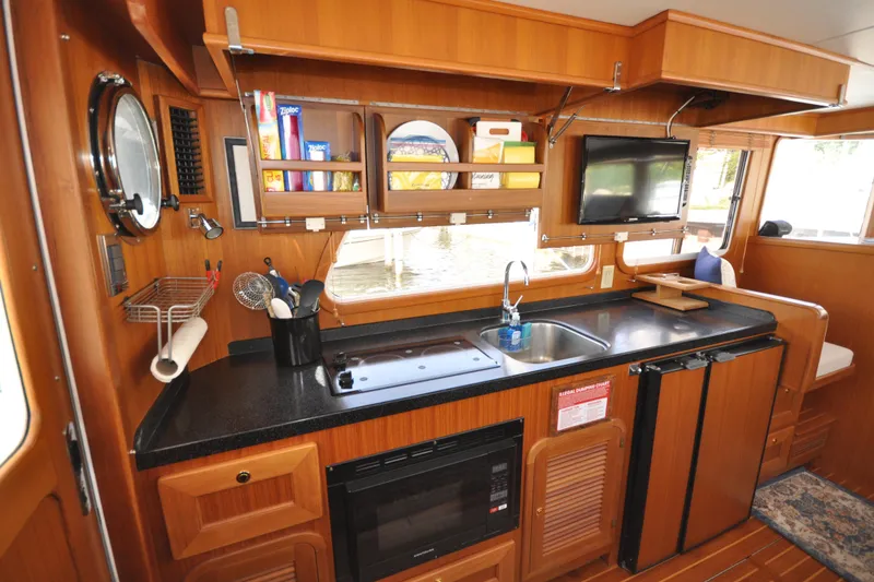Slide: The Image of 2015 Helmsman Trawlers 31 Sedan interior kitchen with wooden cabinetry and modern appliances. - 17
