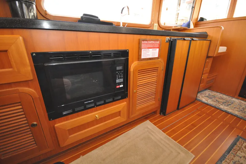 Slide: The Image of 2015 Helmsman Trawlers 31 Sedan interior with microwave and wooden cabinetry. - 18