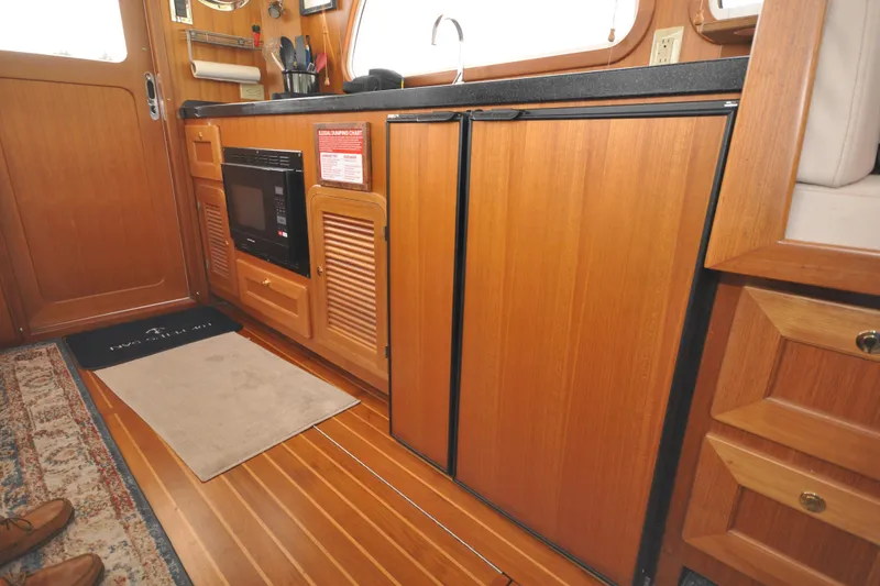 Slide: The Image of 2015 Helmsman Trawlers 31 Sedan interior with wood cabinetry and kitchen appliances. - 19