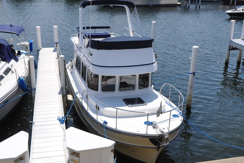 Slide: The Image of 2015 Helmsman Trawlers 31 Sedan docked at marina, featuring sleek design and spacious deck. - 2