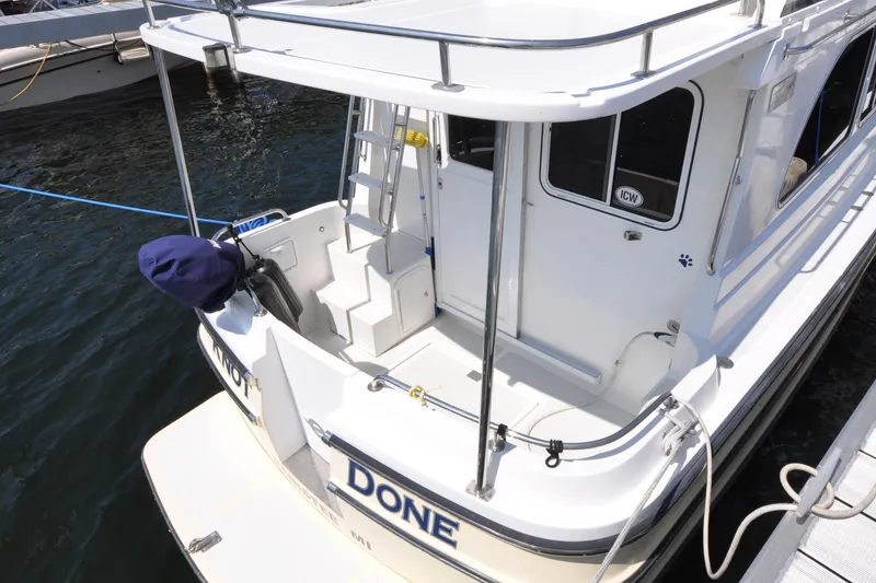 Slide: The Image of 2015 Helmsman Trawlers 31 Sedan boat docked, featuring rear deck and ladder. - 3