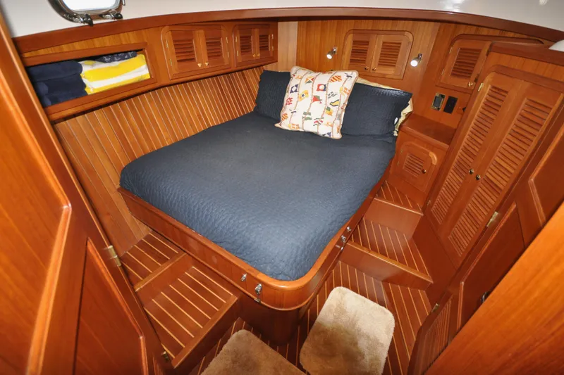 Slide: The Image of 2015 Helmsman Trawlers 31 Sedan cabin with wooden interior and cozy bed. - 31
