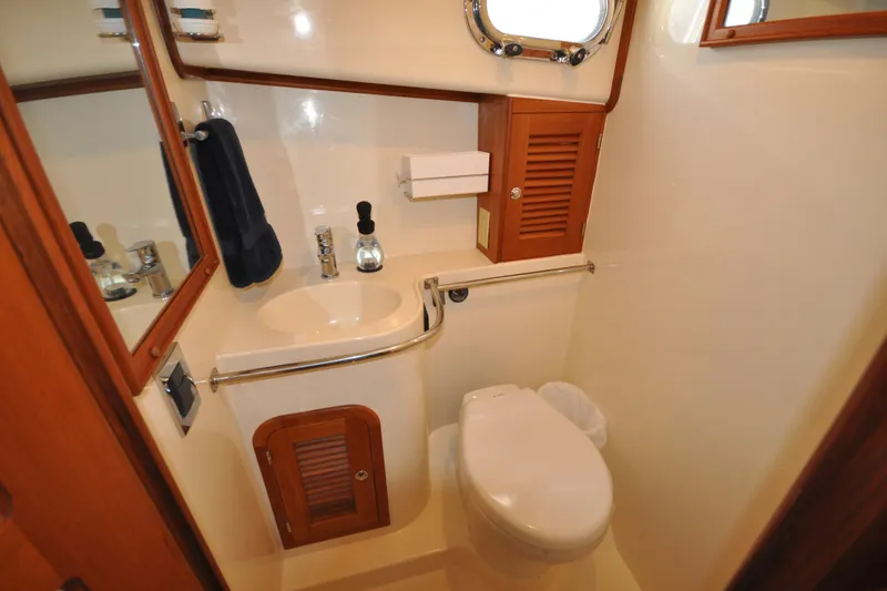 Slide: The Image of 2015 Helmsman Trawlers 31 Sedan bathroom with sink, toilet, and wooden cabinetry. - 36