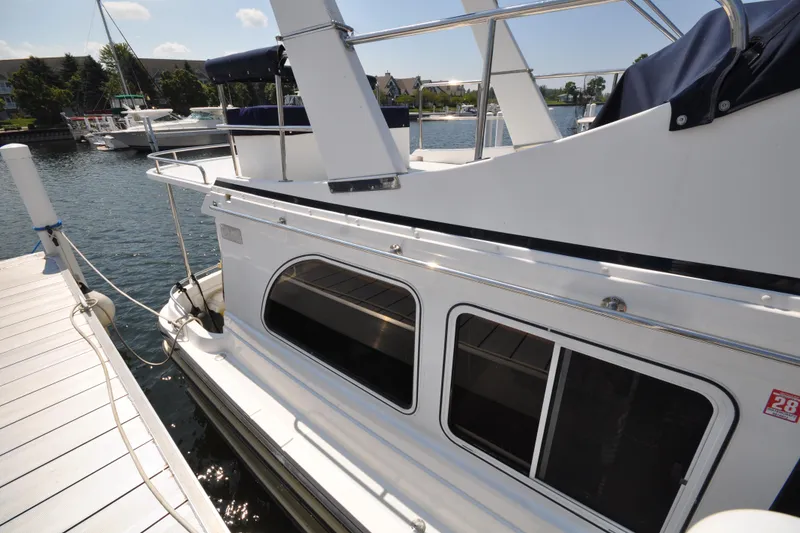 Slide: The Image of 2015 Helmsman Trawlers 31 Sedan docked at a marina, showcasing sleek design and windows. - 5