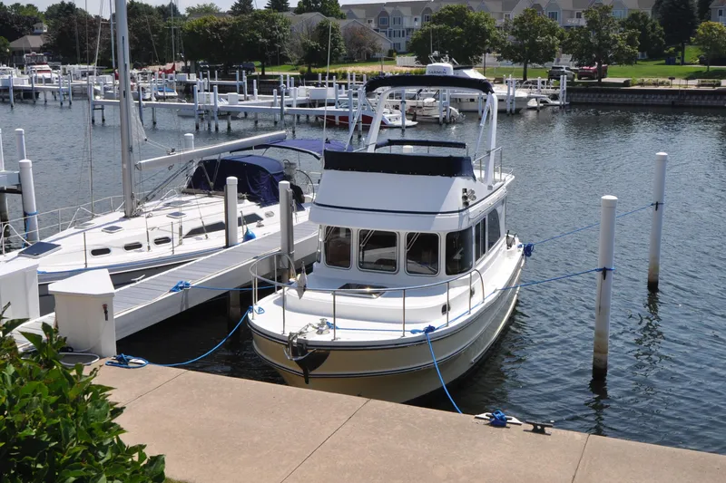 Slide: The Image of 2015 Helmsman Trawlers 31 Sedan docked at a marina, surrounded by sailboats. - 62