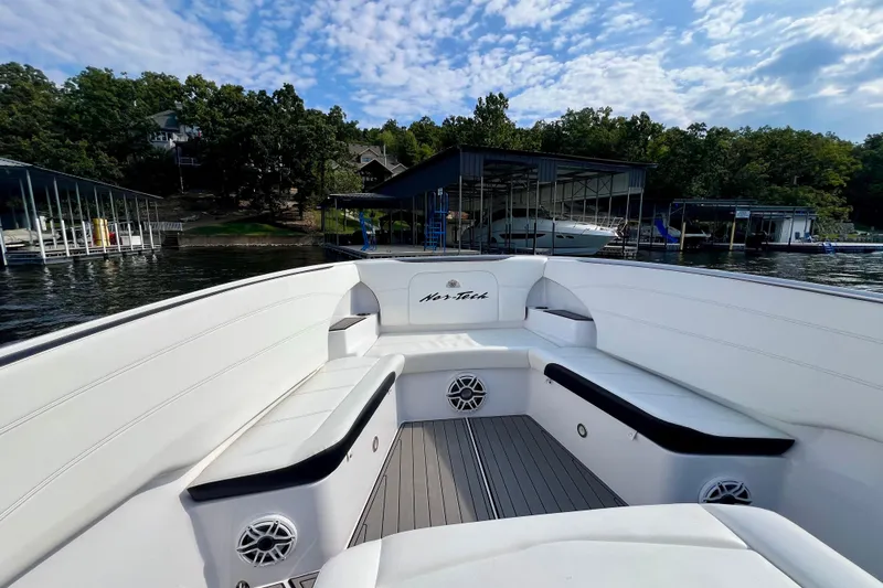 Slide: The Image of 2020 Nor-Tech 340 Sport Center Console boat interior with white seating, docked by a marina. - 24