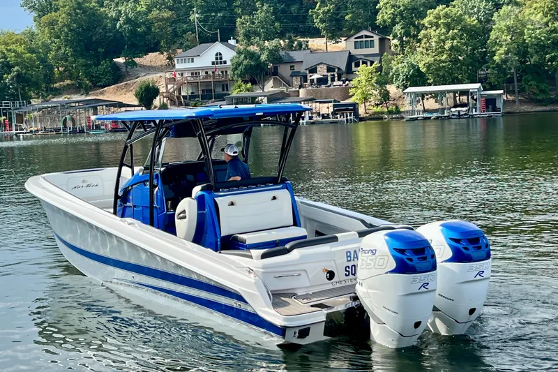 Slide: The Image of 2020 Nor-Tech 340 Sport Center Console boat on a serene lake with lush greenery. - 4