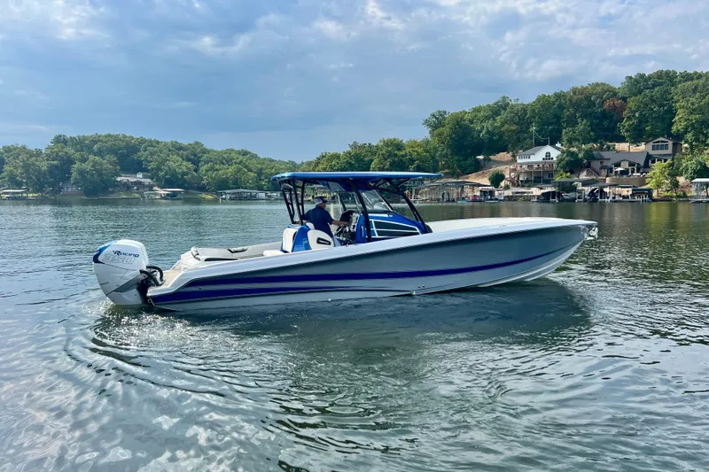 Slide: The Image of 2020 Nor-Tech 340 Sport Center Console boat on a serene lake with lush greenery. - 6
