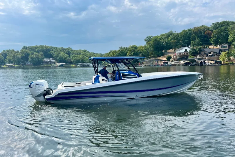 Slide: The Image of 2020 Nor-Tech 340 Sport Center Console boat on a scenic lake with lush greenery. - 8