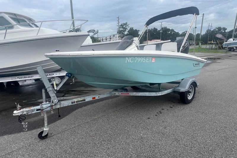 Slide: The Image of 2021 Boston Whaler 130 Super Sport boat on trailer, light blue hull, parked outdoors. - 5