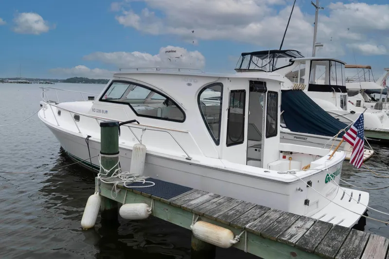 Slide: The Image of 2002 Mainship Pilot 34 Sedan docked at marina with American flag. - 0