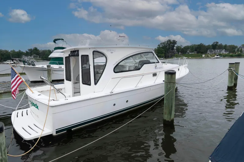 Slide: The Image of 2002 Mainship Pilot 34 Sedan docked, featuring sleek design and American flag. - 1