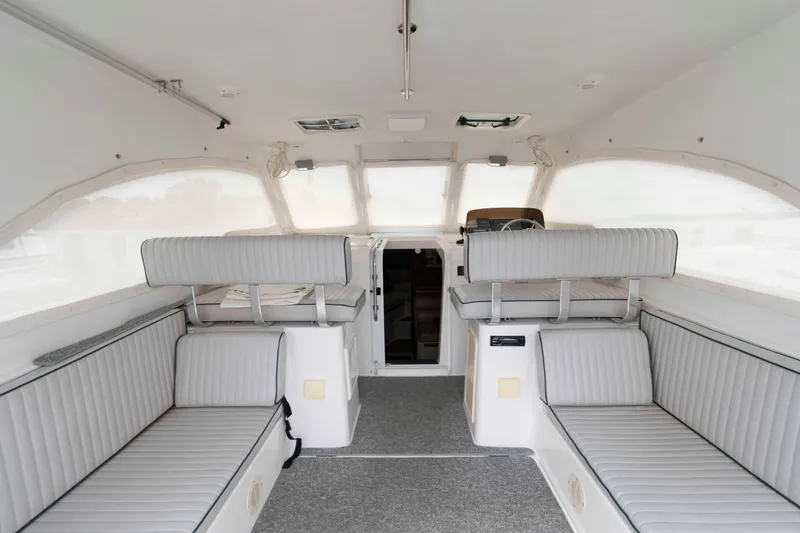 Slide: The Image of Interior of 2002 Mainship Pilot 34 Sedan with white seating and helm area. - 16