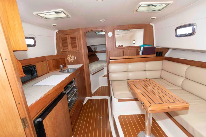 Slide: The Image of Interior of 2002 Mainship Pilot 34 Sedan with cozy seating and compact kitchen area. - 17