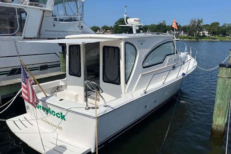 Slide: The Image of 2002 Mainship Pilot 34 Sedan docked, featuring sleek design and American flag. - 2