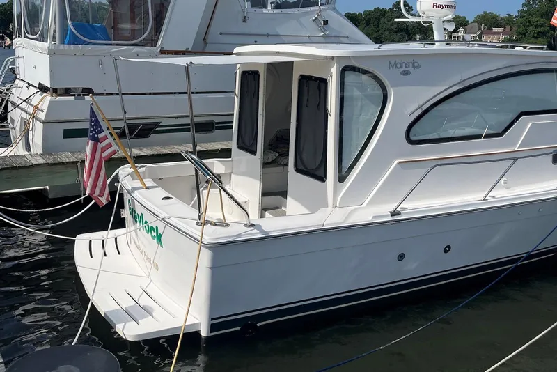 Slide: The Image of 2002 Mainship Pilot 34 Sedan docked, featuring sleek design and American flag. - 3