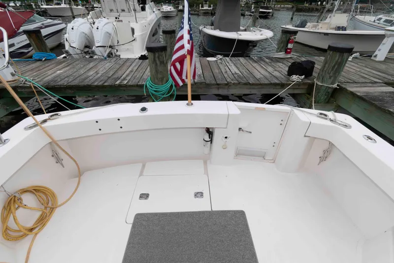 Slide: The Image of 2002 Mainship Pilot 34 Sedan boat docked, featuring spacious deck and American flag. - 4