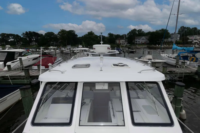 Slide: The Image of 2002 Mainship Pilot 34 Sedan docked at a marina under a partly cloudy sky. - 5