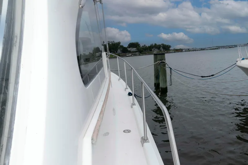 Slide: The Image of 2002 Mainship Pilot 34 Sedan docked by calm waters under a cloudy sky. - 6