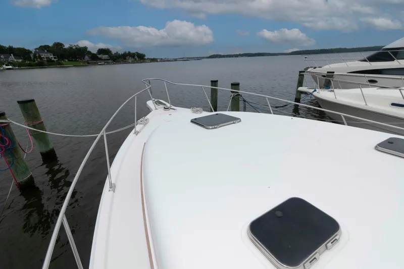 Slide: The Image of 2002 Mainship Pilot 34 Sedan docked, showcasing bow and serene waterfront view. - 7